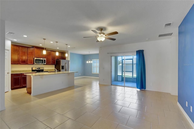 kitchen with appliances with stainless steel finishes, ceiling fan with notable chandelier, sink, a center island with sink, and decorative light fixtures