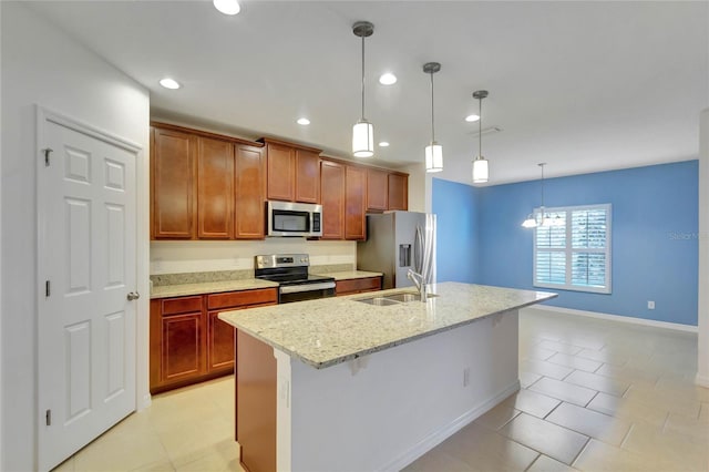 kitchen with pendant lighting, a kitchen island with sink, sink, light stone countertops, and appliances with stainless steel finishes