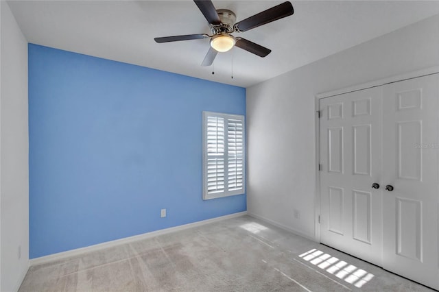 unfurnished bedroom featuring ceiling fan, a closet, and light carpet