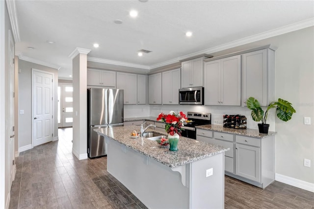 kitchen featuring a kitchen bar, light stone countertops, stainless steel appliances, and an island with sink