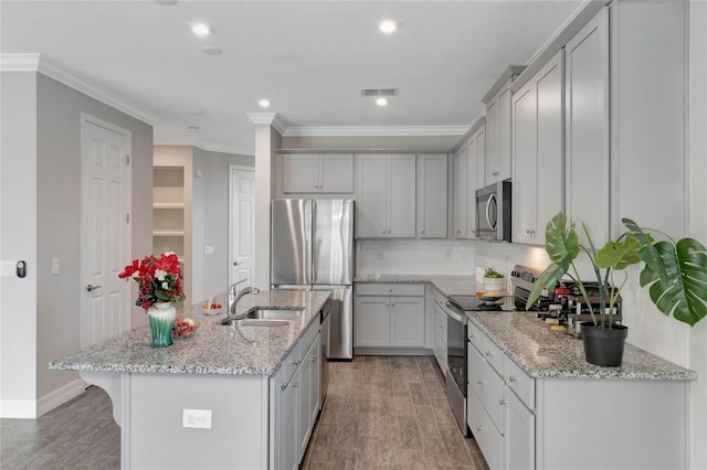 kitchen featuring light stone countertops, stainless steel appliances, a kitchen island with sink, and sink