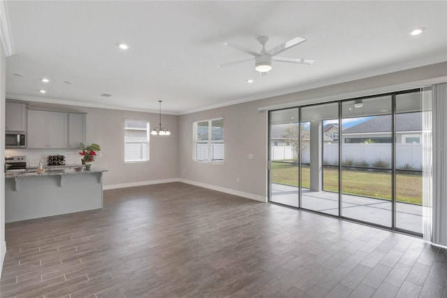 unfurnished living room with ceiling fan with notable chandelier and ornamental molding