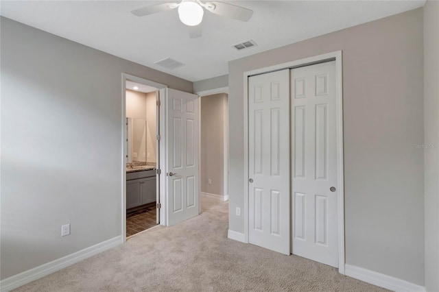 unfurnished bedroom featuring ceiling fan, light colored carpet, ensuite bathroom, and a closet