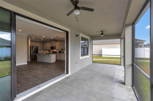 unfurnished sunroom with ceiling fan