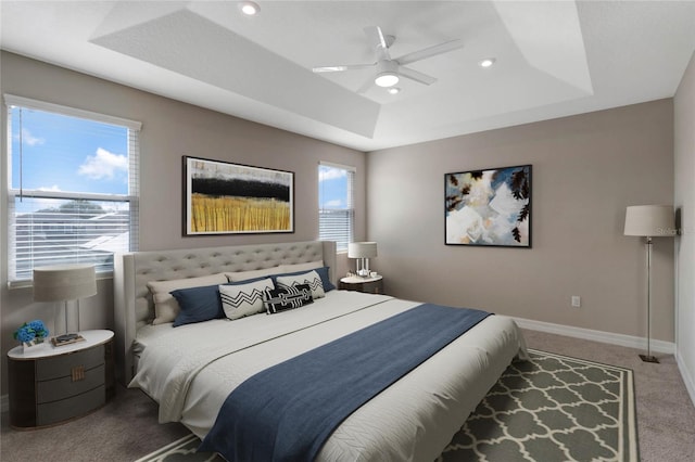 bedroom with carpet flooring, a tray ceiling, and ceiling fan