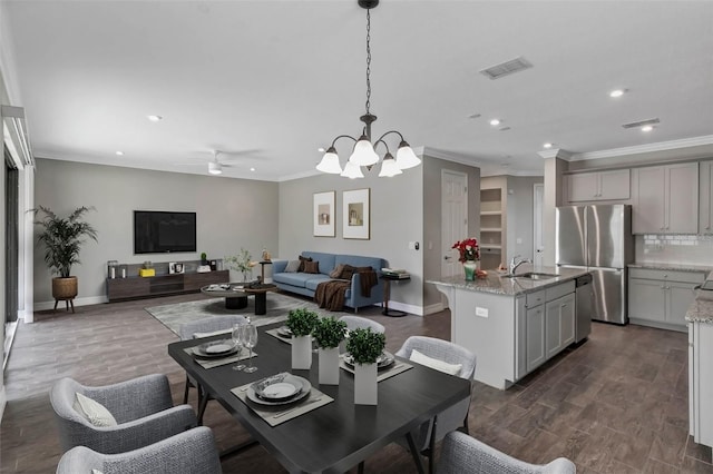 dining space featuring sink, ceiling fan with notable chandelier, and ornamental molding