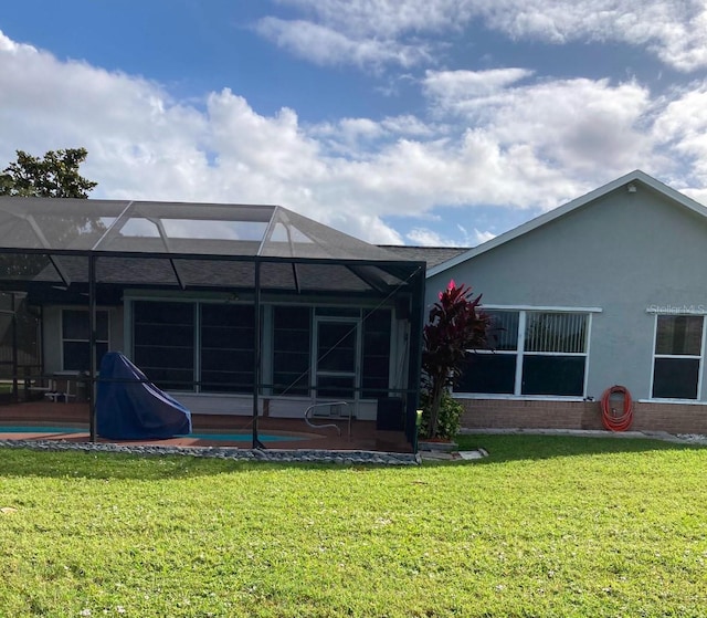 rear view of house featuring a lanai and a lawn