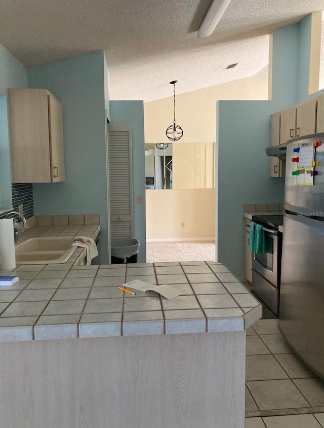 kitchen featuring sink, tile counters, hanging light fixtures, extractor fan, and appliances with stainless steel finishes