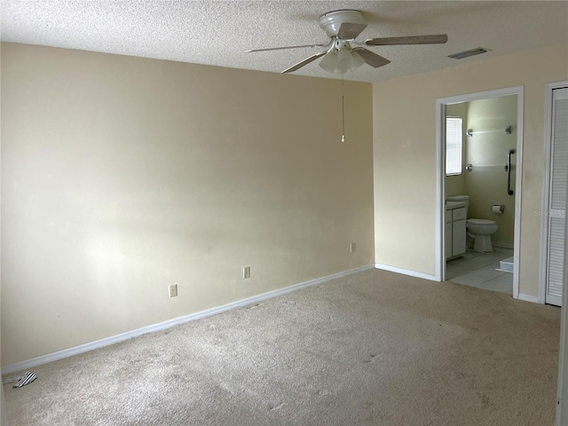 unfurnished room featuring ceiling fan, light colored carpet, and a textured ceiling
