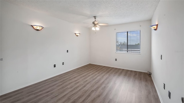 unfurnished room featuring a textured ceiling, ceiling fan, wood finished floors, and baseboards