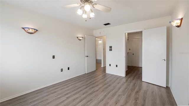 unfurnished bedroom with ceiling fan, visible vents, baseboards, a spacious closet, and light wood finished floors