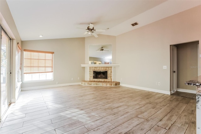 unfurnished living room with a tile fireplace, ceiling fan, vaulted ceiling, and light wood-type flooring