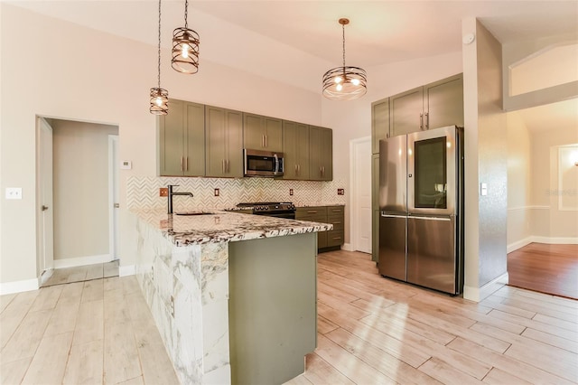 kitchen featuring sink, light wood-type flooring, appliances with stainless steel finishes, light stone counters, and kitchen peninsula