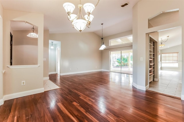 unfurnished room with hardwood / wood-style flooring, a notable chandelier, and vaulted ceiling