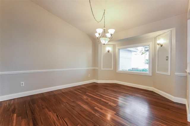 empty room featuring a notable chandelier, lofted ceiling, and dark wood-type flooring