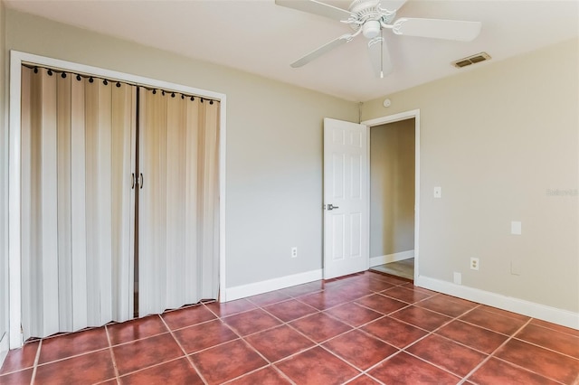 unfurnished bedroom featuring dark tile patterned flooring, ceiling fan, and a closet