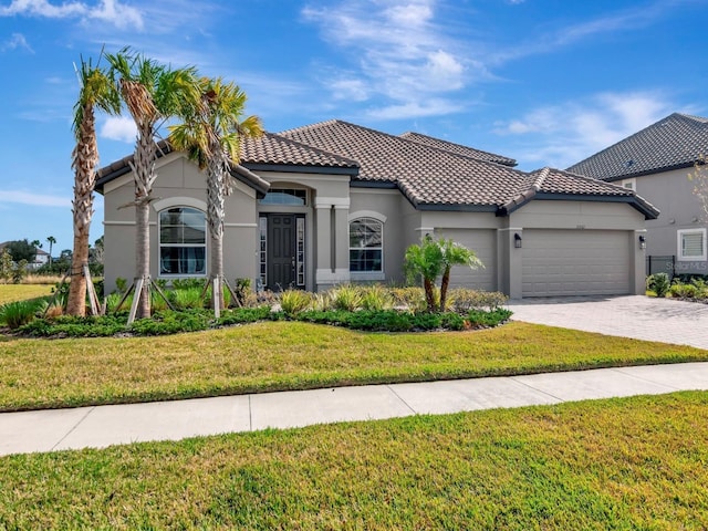 mediterranean / spanish-style home featuring a front lawn and a garage