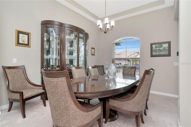 dining space featuring a raised ceiling, light colored carpet, and a chandelier