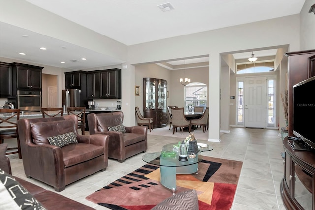 tiled living room featuring crown molding and a chandelier