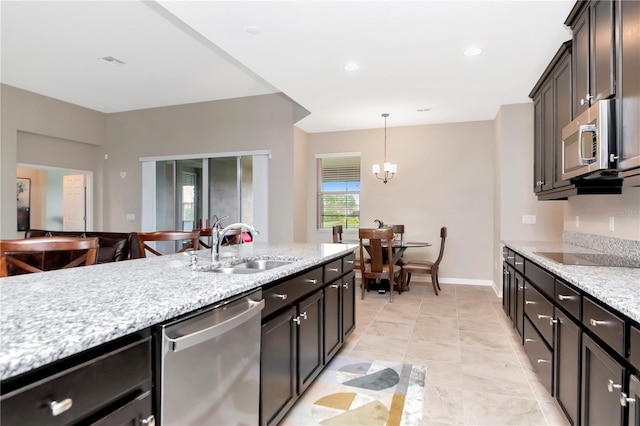 kitchen featuring sink, stainless steel appliances, a notable chandelier, light stone countertops, and decorative light fixtures