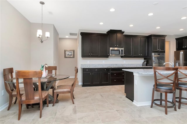 kitchen with pendant lighting, a kitchen bar, a center island, light stone counters, and stainless steel appliances