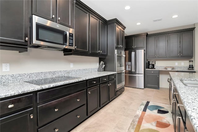 kitchen with light stone counters, light tile patterned flooring, and appliances with stainless steel finishes