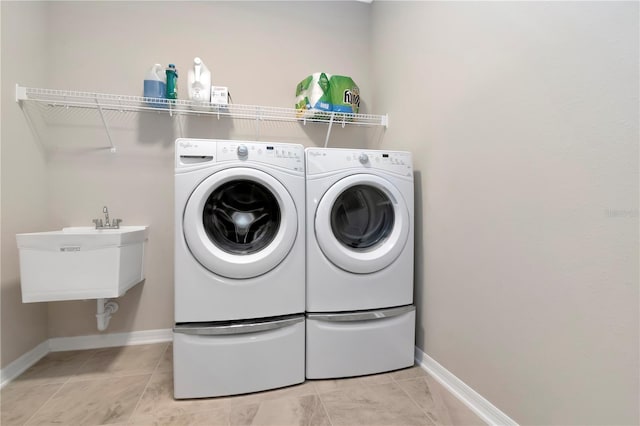 clothes washing area with light tile patterned floors, sink, and washing machine and clothes dryer