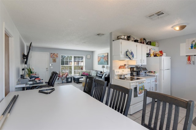 kitchen with white cabinets, white appliances, a textured ceiling, and light tile patterned floors