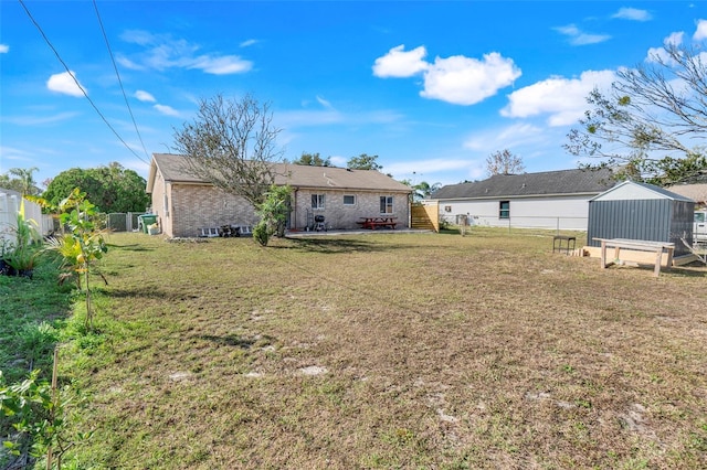 rear view of house featuring a lawn and a storage unit