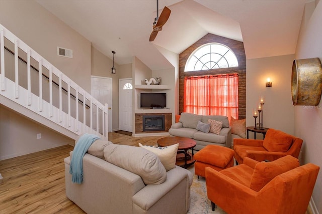 living room with ceiling fan, high vaulted ceiling, and light wood-type flooring