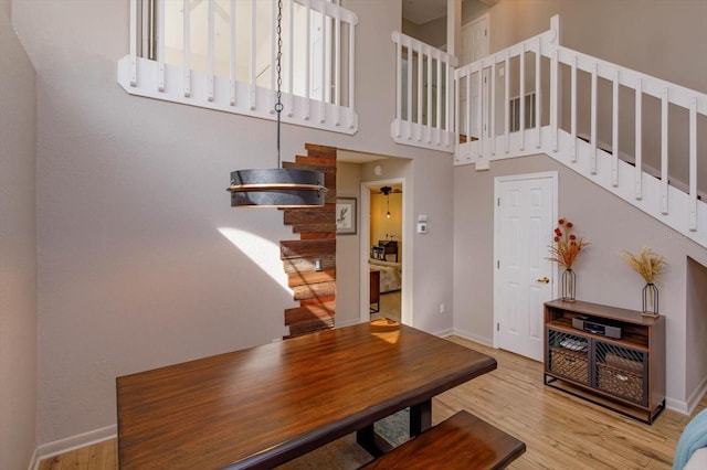 dining area featuring a towering ceiling and light wood-type flooring