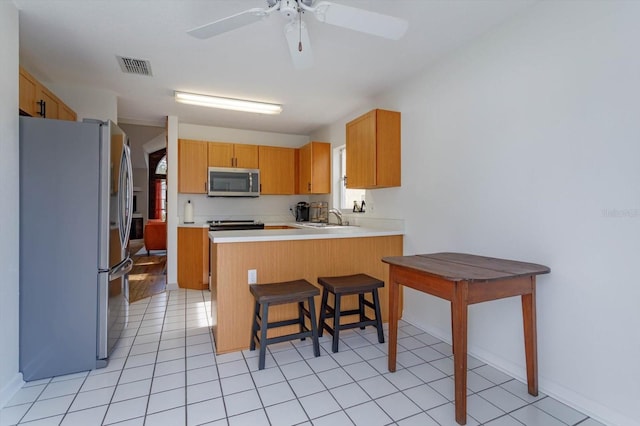 kitchen featuring a breakfast bar, sink, appliances with stainless steel finishes, kitchen peninsula, and ceiling fan