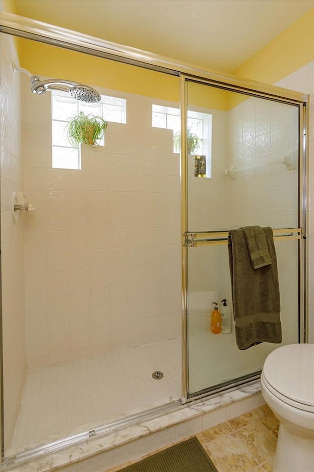 bathroom featuring tile patterned flooring, an enclosed shower, and toilet