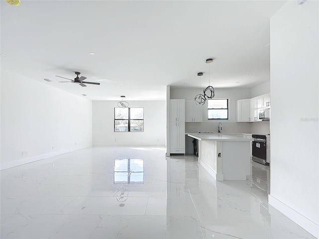 kitchen featuring a center island, stove, white cabinets, ceiling fan, and decorative light fixtures