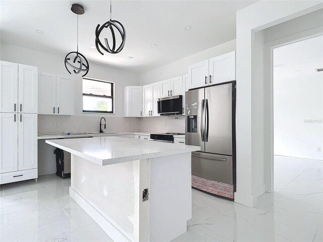 kitchen featuring decorative backsplash, stainless steel appliances, white cabinetry, a kitchen island, and hanging light fixtures