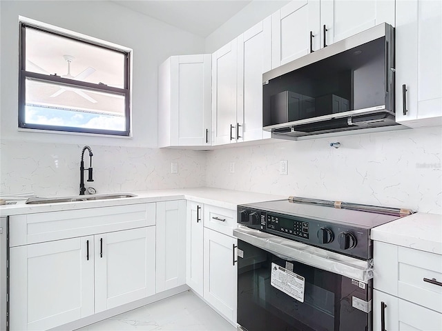 kitchen with sink, stainless steel appliances, tasteful backsplash, light stone counters, and white cabinets