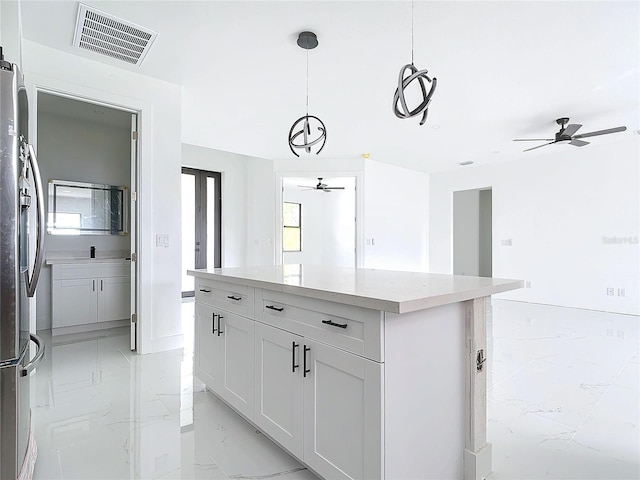 kitchen featuring white cabinetry, stainless steel fridge, a kitchen island, and decorative light fixtures