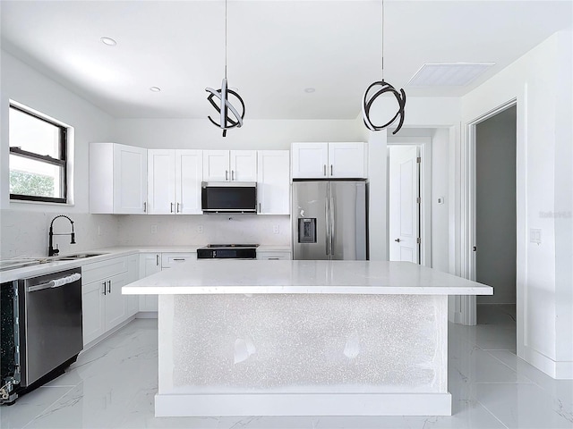 kitchen with white cabinets, a center island, hanging light fixtures, and appliances with stainless steel finishes