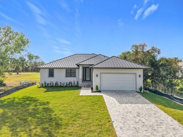 16760 Acapulco Rd, Punta Gorda, FL 33955 - view of front of house featuring an attached garage, stucco siding, a metal roof, driveway, and a standing seam roof