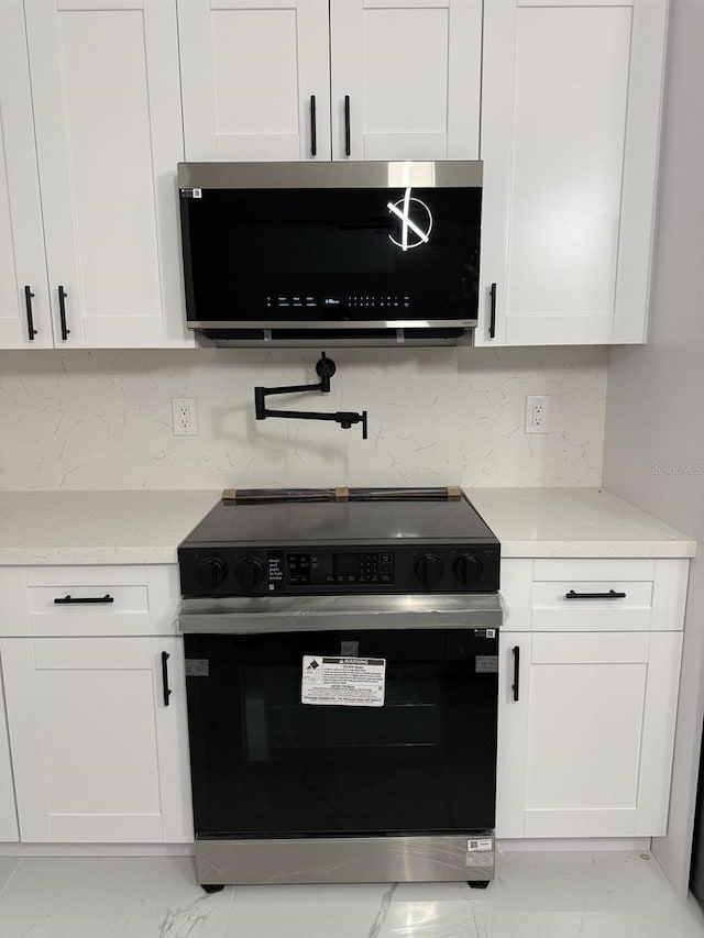 16760 Acapulco Rd, Punta Gorda, FL 33955 - kitchen featuring electric range oven, stainless steel microwave, white cabinetry, and backsplash