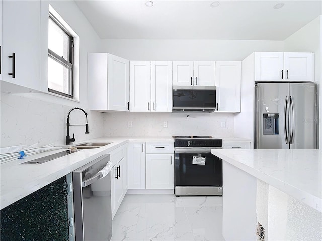 16760 Acapulco Rd, Punta Gorda, FL 33955 - kitchen with stainless steel appliances, white cabinets, light stone countertops, light marble finish flooring, and decorative backsplash