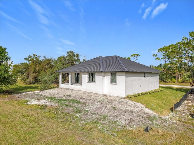 16760 Acapulco Rd, Punta Gorda, FL 33955 - rear view of property featuring stucco siding, a lawn, and a metal roof