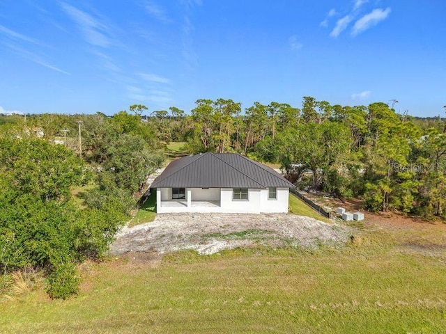 16760 Acapulco Rd, Punta Gorda, FL 33955 - back of house featuring a yard, a metal roof, and a wooded view