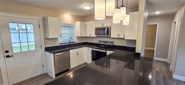 kitchen with appliances with stainless steel finishes, decorative light fixtures, white cabinetry, and sink