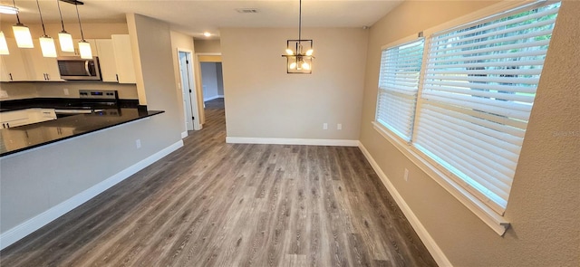 kitchen with appliances with stainless steel finishes, pendant lighting, a notable chandelier, dark hardwood / wood-style floors, and white cabinetry