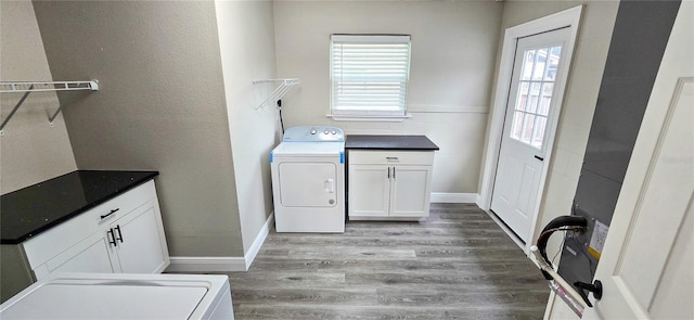 clothes washing area with cabinets, washing machine and dryer, light hardwood / wood-style flooring, and a wealth of natural light