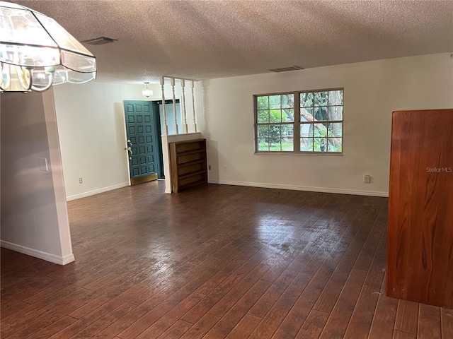 unfurnished living room with dark hardwood / wood-style flooring and a textured ceiling