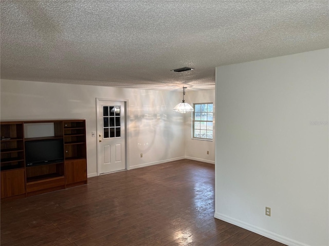 unfurnished living room with dark hardwood / wood-style flooring and a textured ceiling