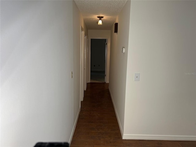 corridor featuring dark wood-type flooring and a textured ceiling