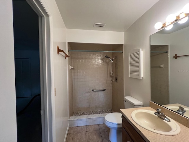 bathroom featuring tile patterned floors, vanity, toilet, and tiled shower